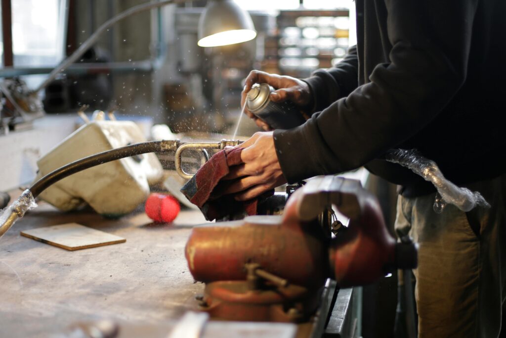 A mechanic uses a spray on equipment in a busy workshop environment.