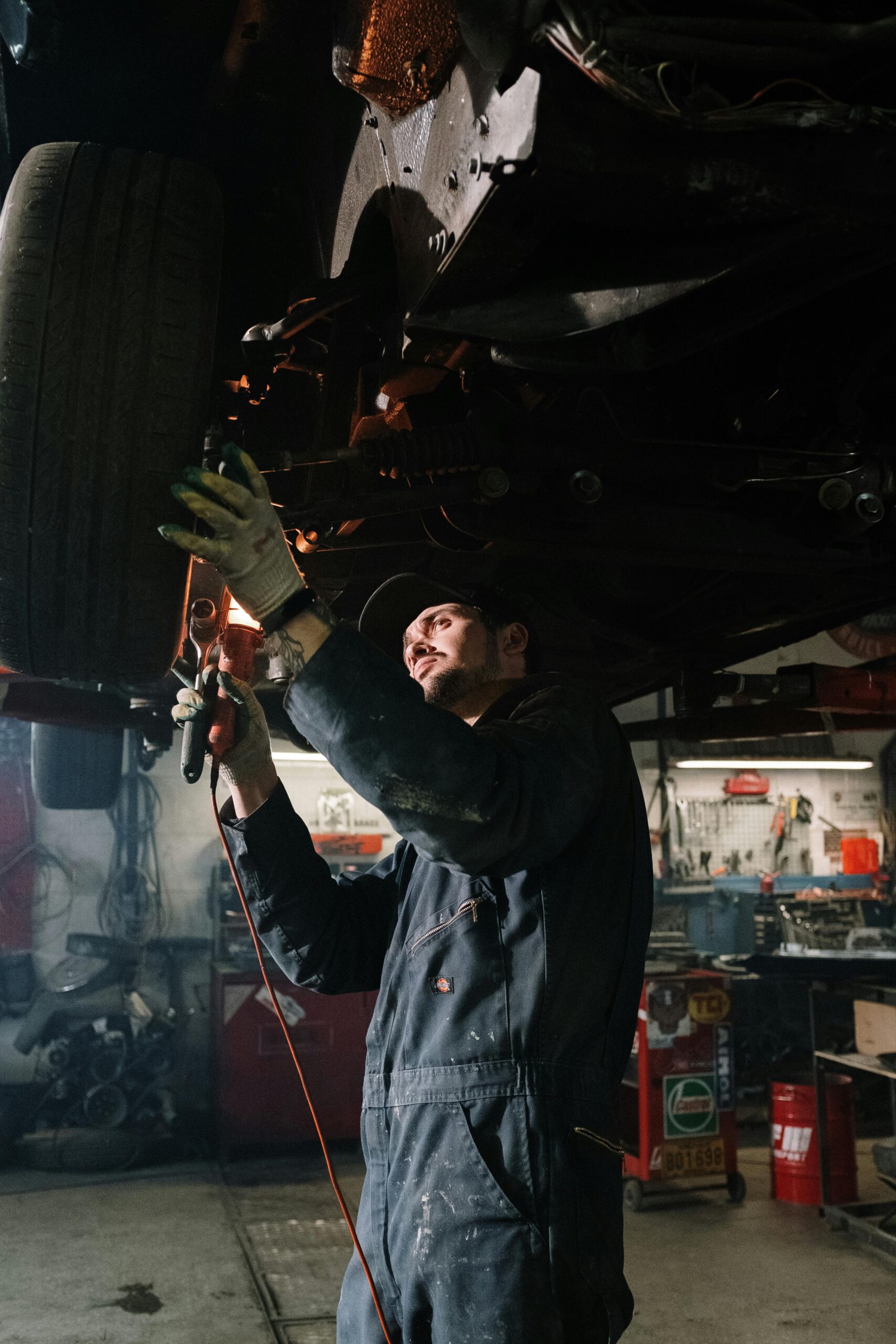 Mechanic working on a car maintenance in a well-equipped garage setting.