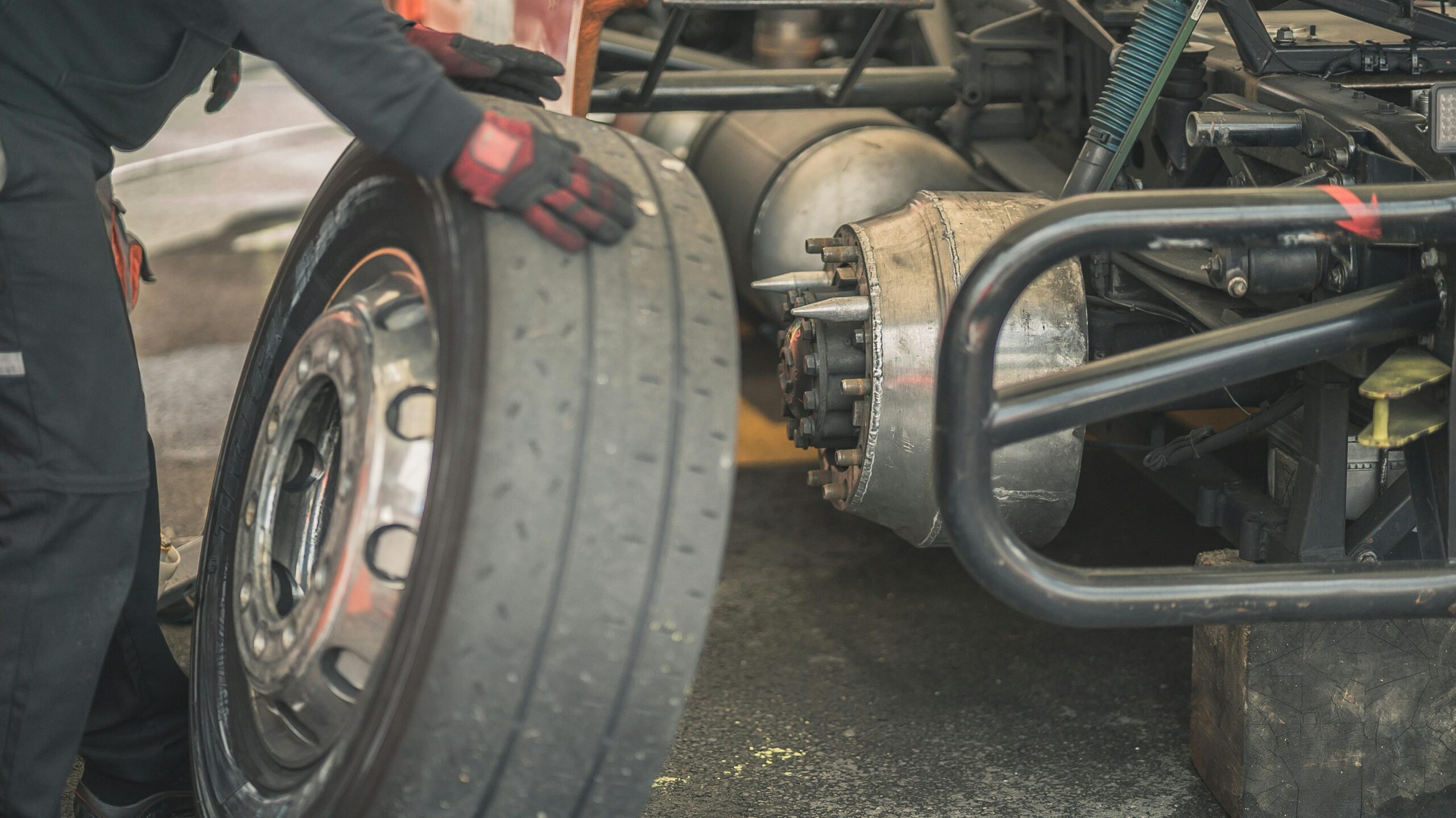 Mechanic working on replacing a tire in a professional automotive garage setting.