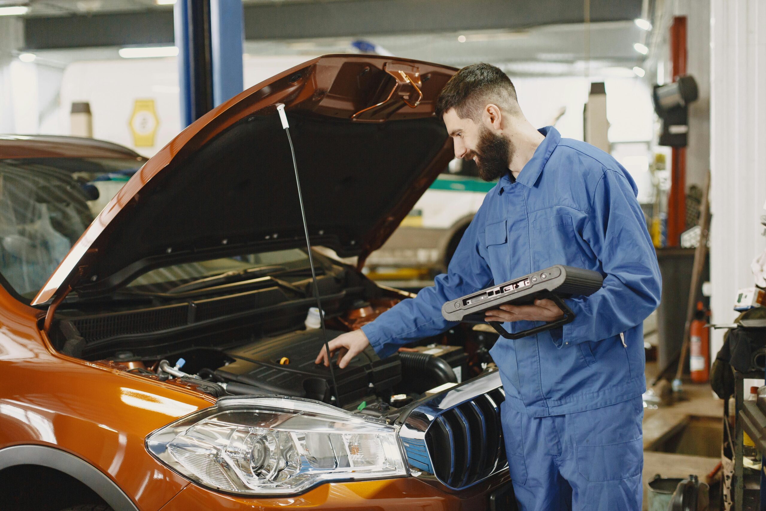 Skilled mechanic working on car engine diagnostics in a modern garage.